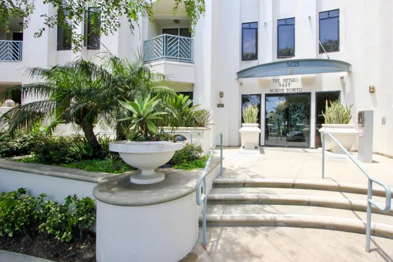 The Metro, playa vista, California is A beautiful entrance with pretty good gate and lots of greenery including plants and trees. Colourfull flowers are adding life in the picture.