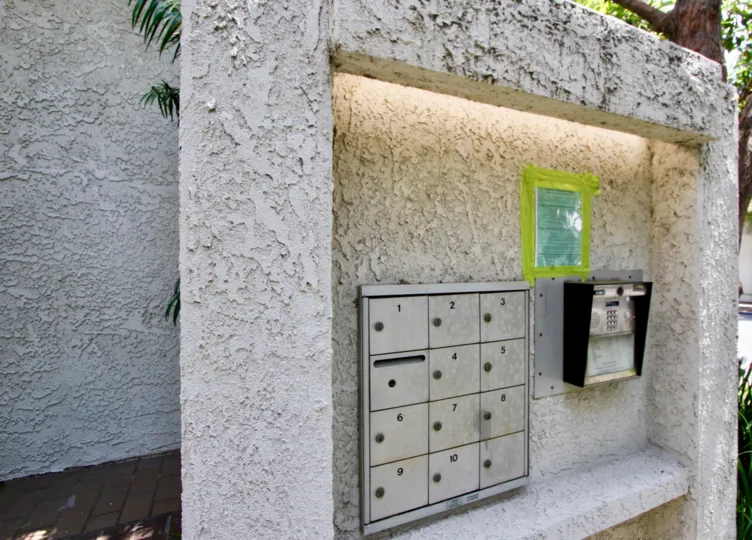 An arrange of mailboxes in the 1037 16th St community with trees and plants in the background.