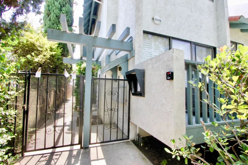 The security gate of 1144 7th St with bushes on either side