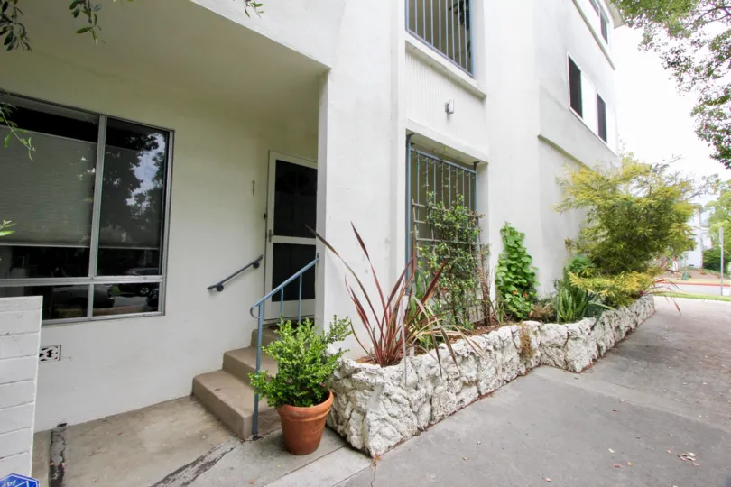 A white building in the 1225 Washington community surrounded by plants