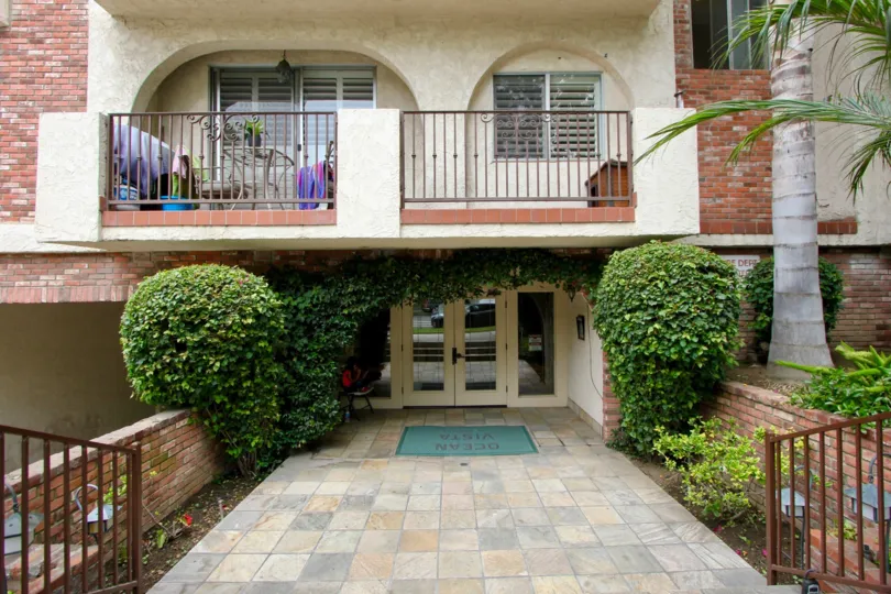 A brick apartment building with a balcony with palm trees and pushes at 125 Montana Ave in Santa Monica.