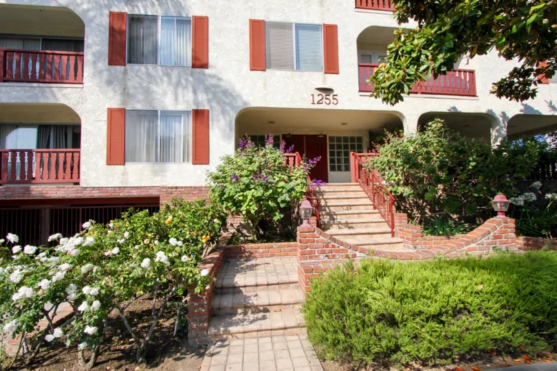 A white building on 1255 10th St. building in the sunlight, surrounded by lots of foliage in in Santa Monica.