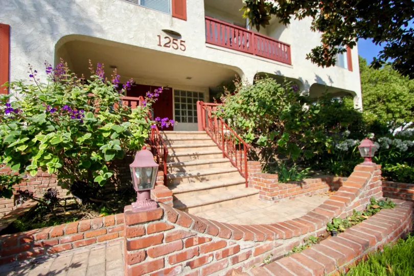 A bricked entranced in 1255 10th St. community flanked by overgrown shrubs.