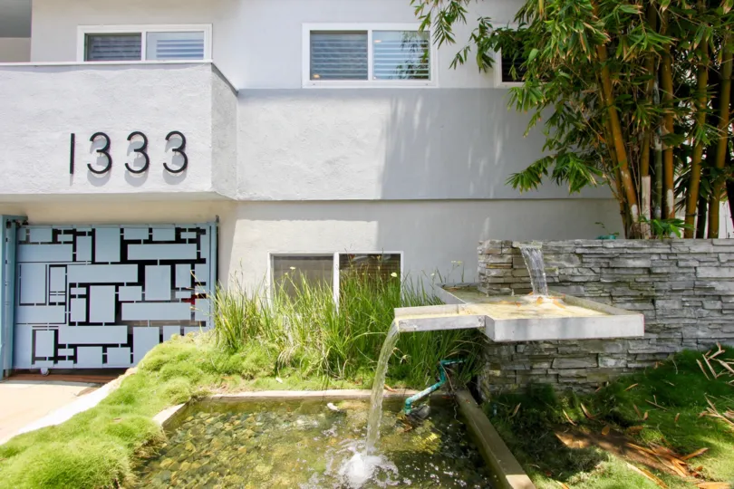 Lawn outside 1333 14th St building with a fountain and palm trees.