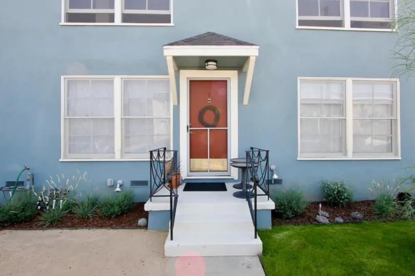 A blue house in the 2314 28th St community with a red front door and white windows