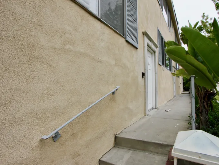 Pathway to an 425 Idaho building with a palm tree to the right on a cloudy day.