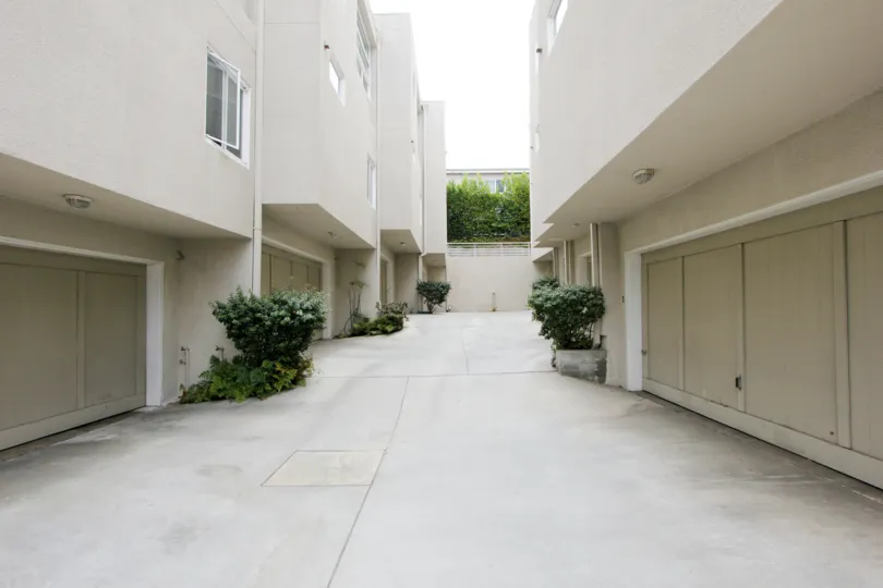 Pathway between two white 650 buildings with potted plants on the outside