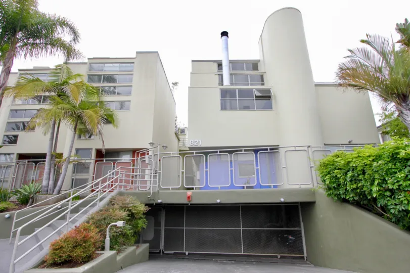 A grey building in the 921 Bay St community with trees and plants around it