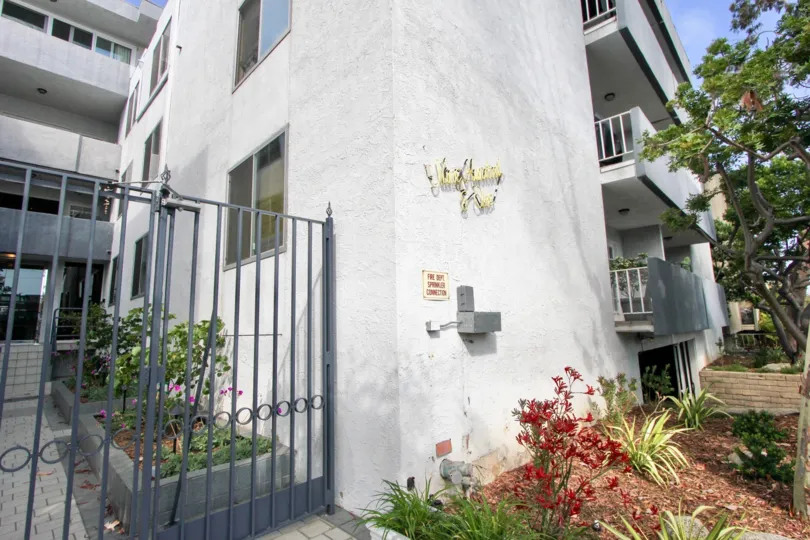 A white building in the 901 10th St community with a black fence and red flowers