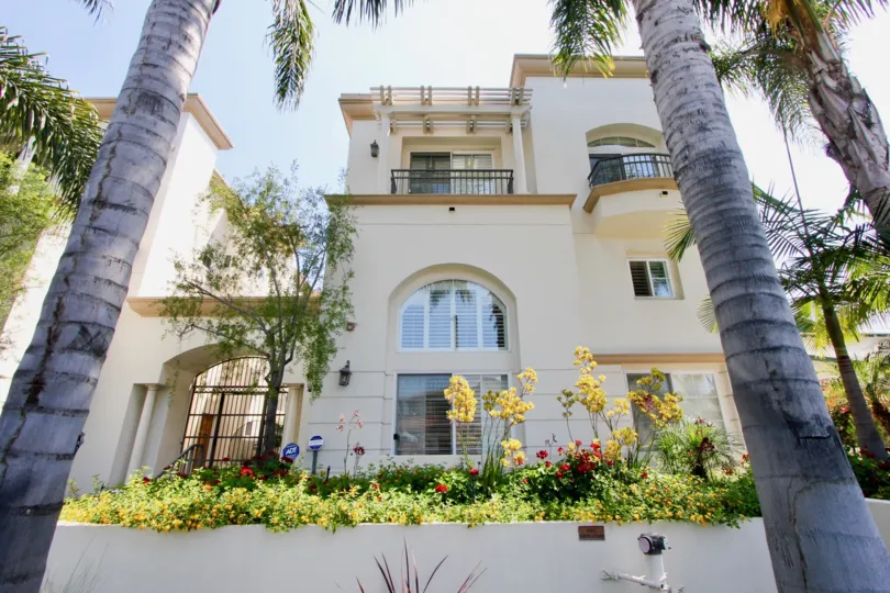 The house in the Berkeley Manor looks very big and has so many yellow and red small flowers in front of the house.