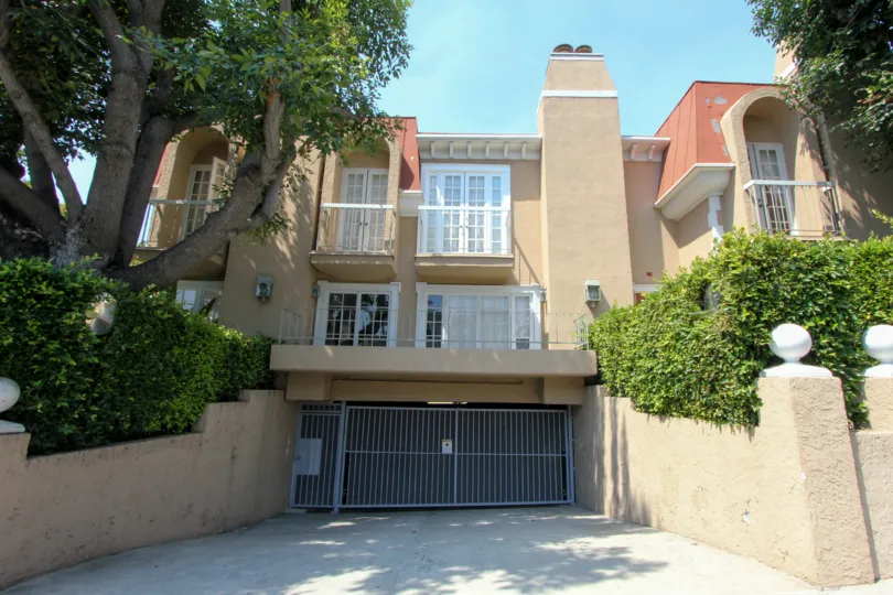 A BUILDING WITH A SMALL GATE INFRONT OF AND ALSO CLOSED SOME GREEN PLANTS ALSO NEAR TO THE HOUSE.
