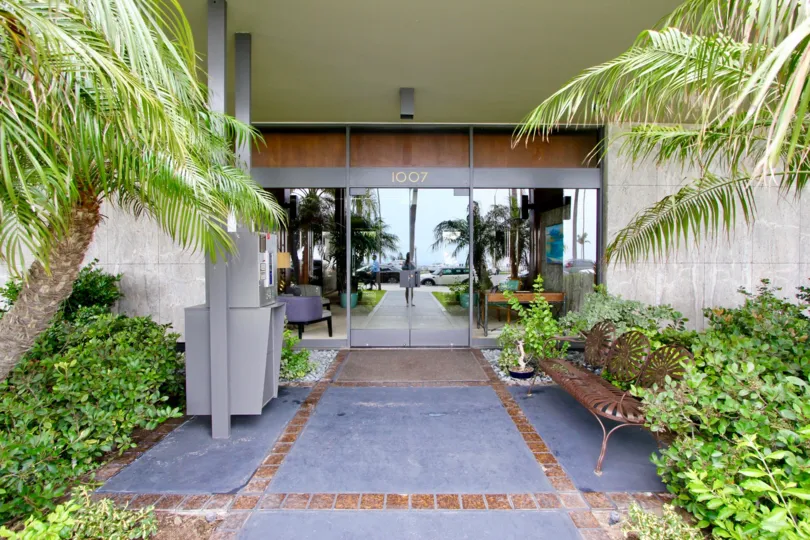 A tiled porch to the Boca Monica community with iron bench on the side.