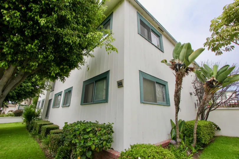 A white house in the Euclid Condominiums community surrounded by green grass and plants