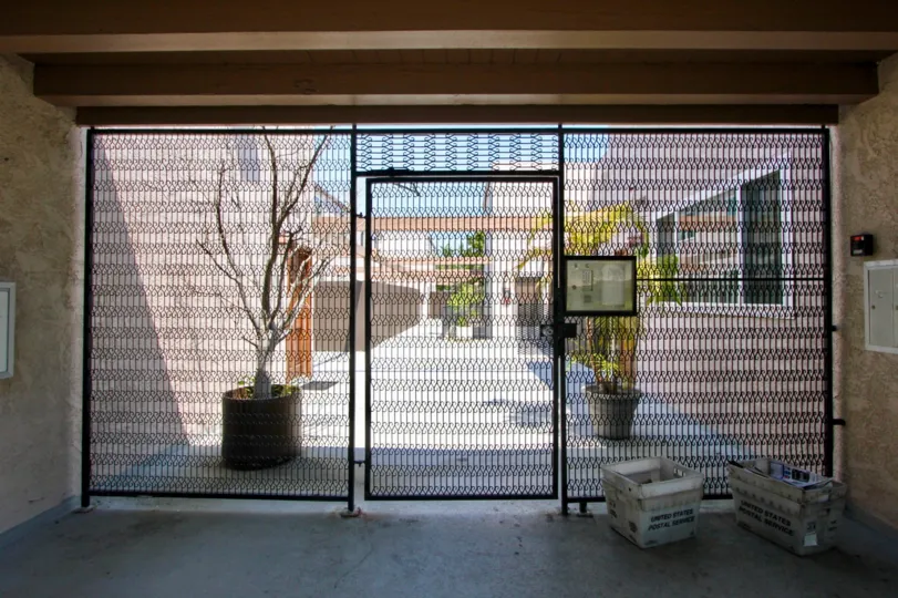 GATES WITH PLANTS AND AN ENTRANCE ALSO AVAILABLE SOME BUILDINGS LOCATED BOTH SIDE OF THE ENTRANCE.