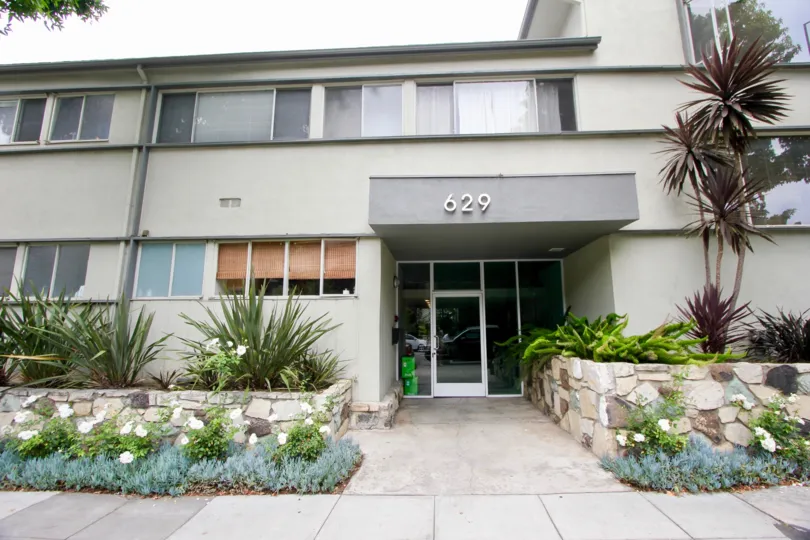 A grey colored house with number 629 and glass windows and doors. Fancy grass and bushes on front.