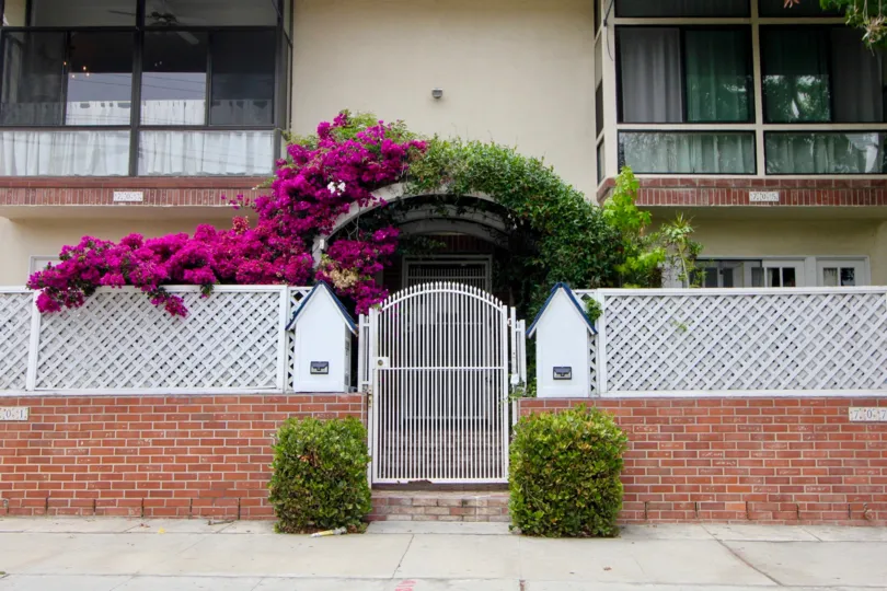 Street front of a residence in the La Belle Monique community with pink flowers and white fence