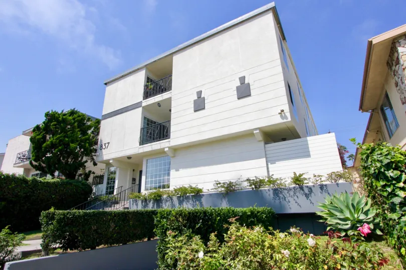 A three level living community on a bright sunny day surrounded by beautiful greenery.