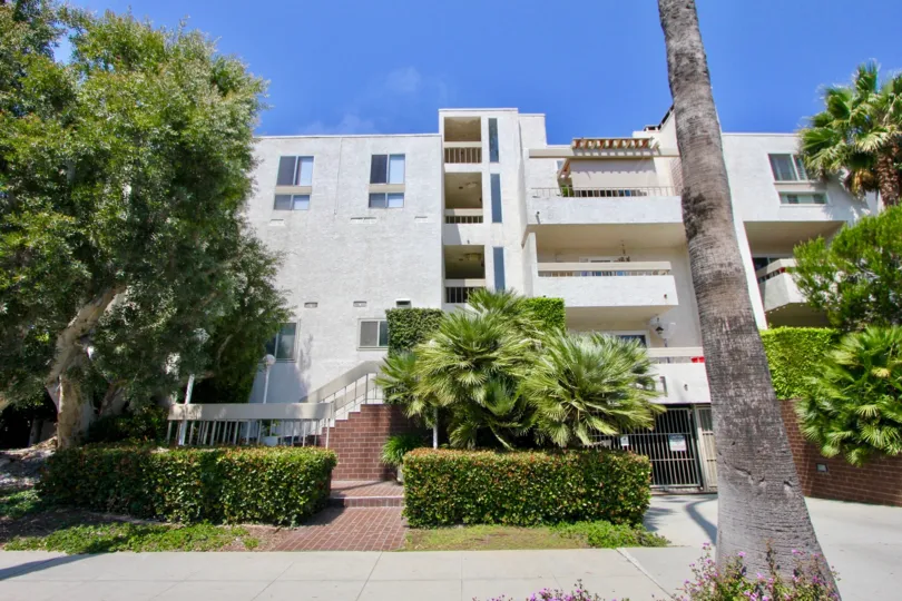 A grey building in the Ocean Plaza community with green trees and multiple balconies