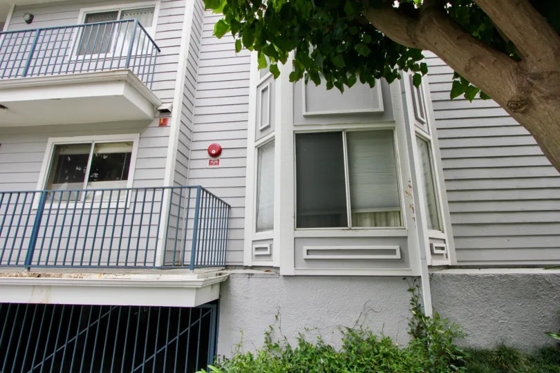 A grey building in the Pacific Gardens community with blue guard rails and white trim