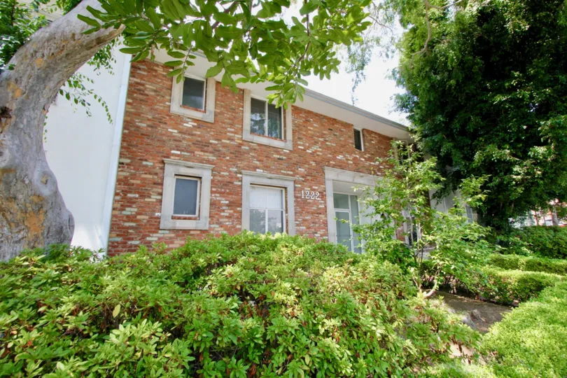 A sunny day in the Princeton South community with a red brick house and plants
