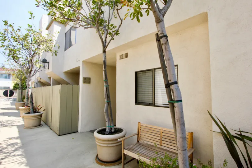 The wide campus of Santa Monica Townhomes with a wooden bench and pots on front side