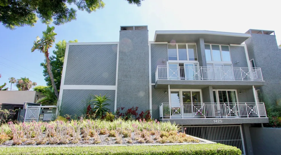 A grey house in the Stanford Gardens neighborhood with two balconies and two chimneys
