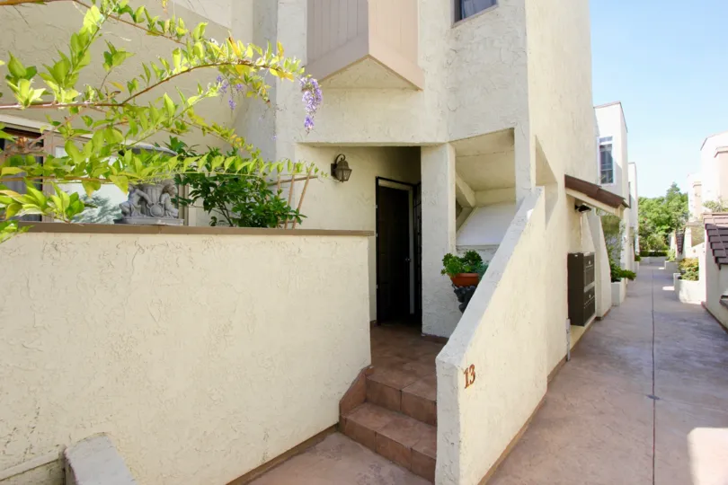 Ground level front door facing view from the Stanford Complex walkway, with courtyard wall and patio area visible