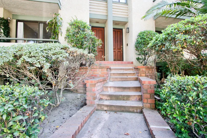 Front steps leading up to Villa Centinela in Santa Moncia surrounded by trimmed and artfully positioned trees.