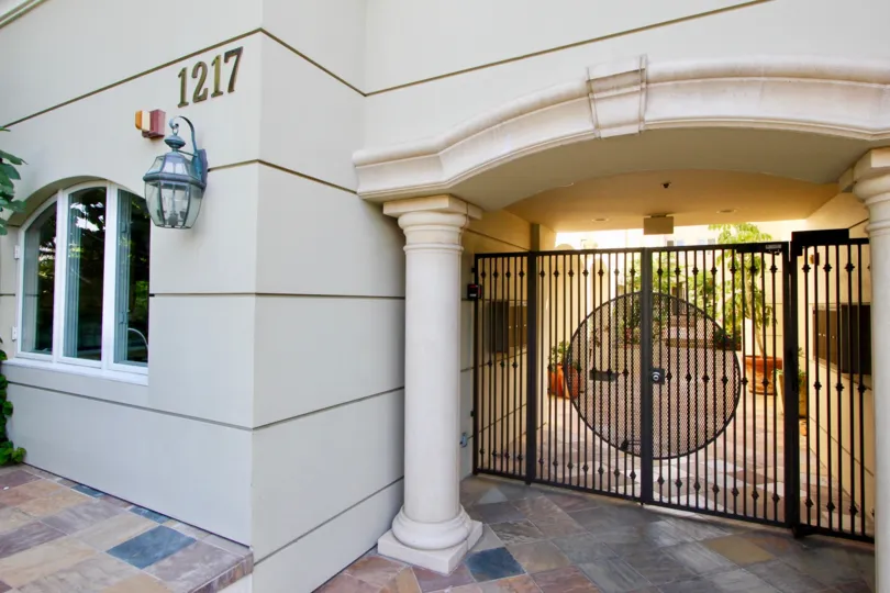 A white building in the Villa Toscana community with a large white pillar and black gate