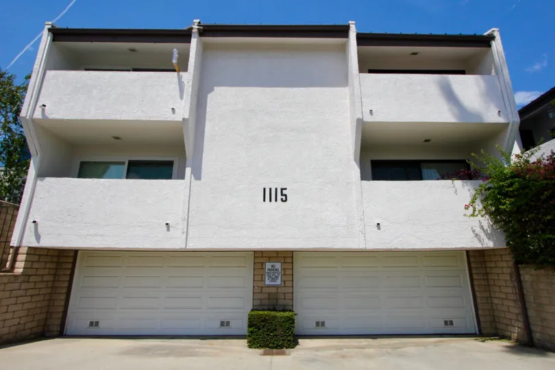 The back of a villa with parkingwith a number 1115 in Village Green