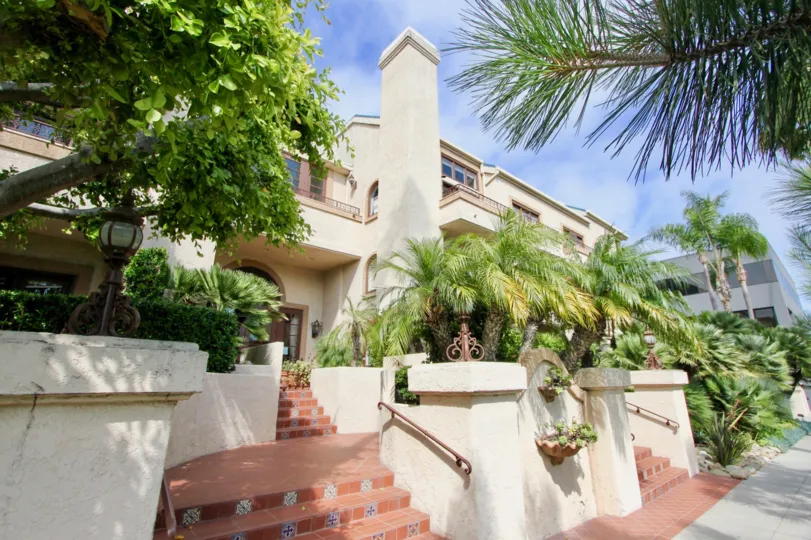 Elegant two story apartment building with balconies on the upper floor and a brick divided stairway leading to the street.