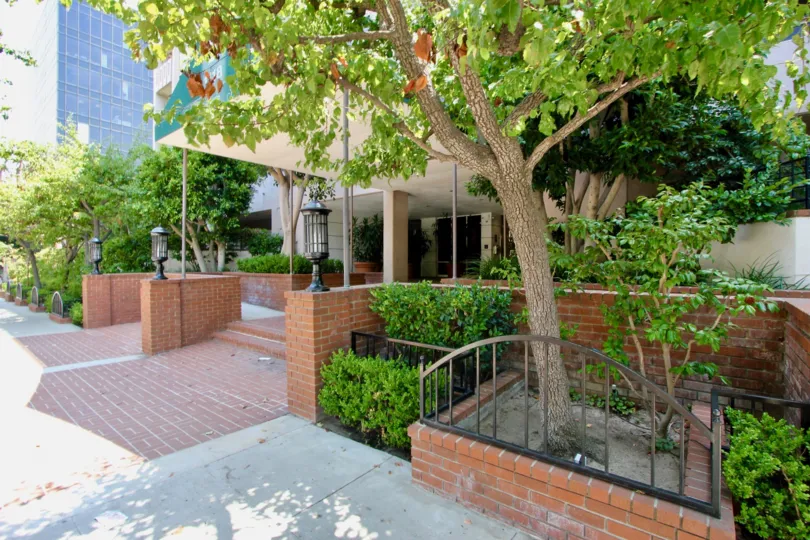 Front entrance to Wilshire Ocean Terrace with brick covered pathwayy and nice lamps with trees.