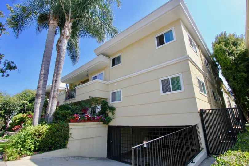 A yellow house in the Yale Street Condos community with black rails and palm trees