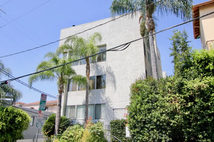 a white building in 1021 Westmount with palm trees in the front