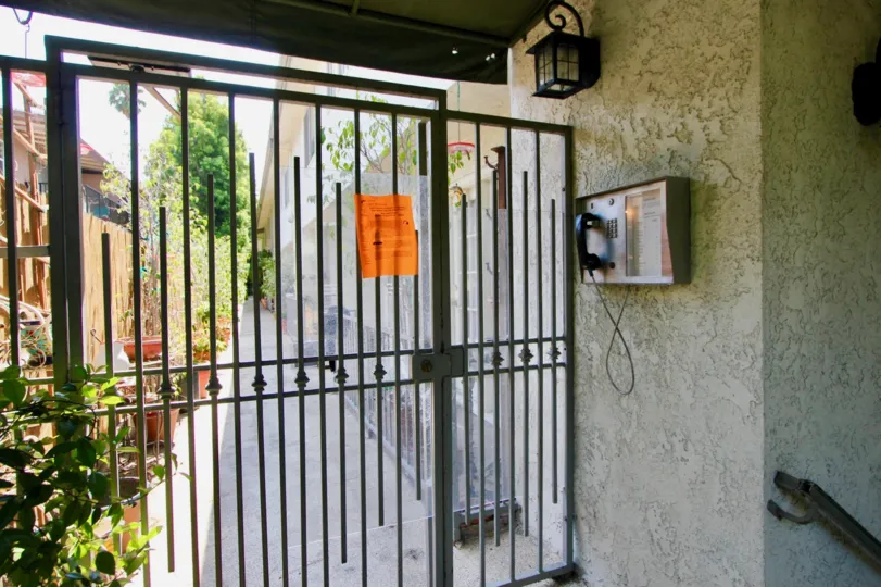 Locked gate in 944 Palm with a telephone and an alleyway behind it