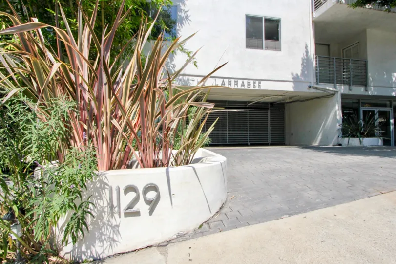 1129 numbered Larrabee building with red colored shrubs and big gate.