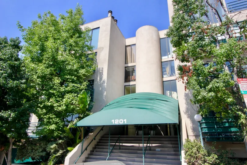 Large trees and blue skies surround the covered front steps of the Vista Larrabee community in West Hollywood, California