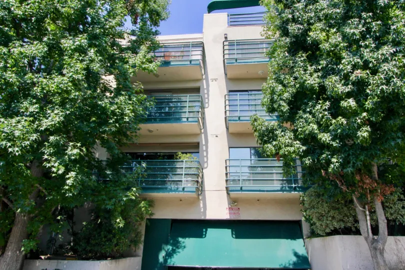 A white building in the Vista Larrabee neighborhood with tall trees and six balconies