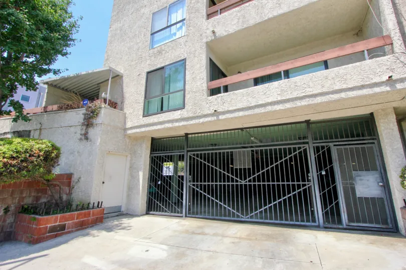 A BUILDING WITH A LARGE SIZE ENTRANCE GATE AND TWO FLOORS SOME TREES NEAR TO THE PLACE AT THE MORNING TIME
