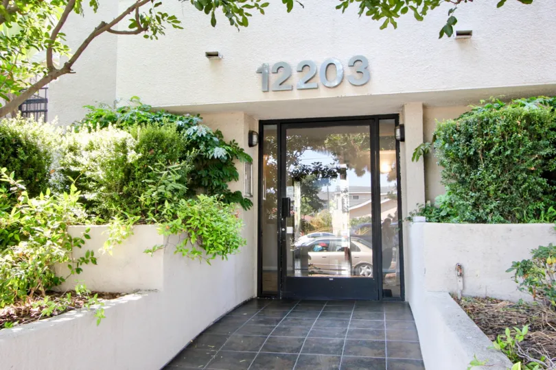 12203 Idaho, west la, California is A beautiful entrance with pretty good gate and lots of greenery including plants and trees. Colourfull flowers are adding life in the picture.