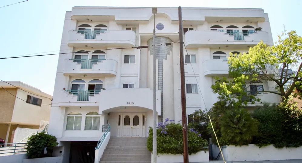 Front exterior view of 1315 Saltair complex in sunny West LA, California with some trees and bushes