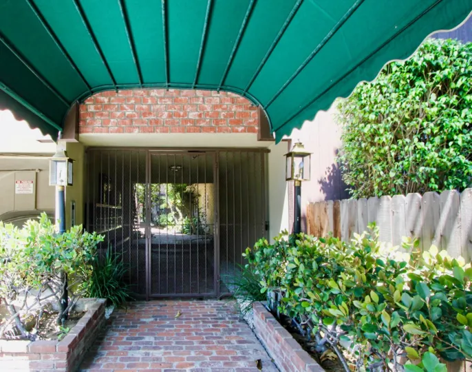 The gated entrance to a building, underneath a green awning in the 1722 Brockton community in West LA, California