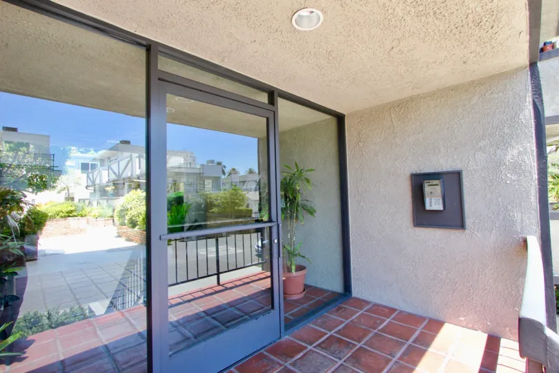 A see-through glass door in the 1914 cornight community. there is an intercom outside the door.