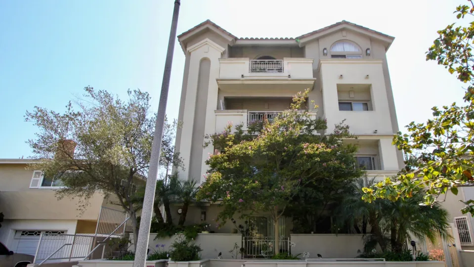 A sunny day in the Armacost Royal with beautiful apartment and big tree infrond of apartment.