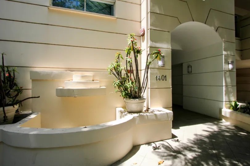 White brick and dry fountain and potted succulents entrance with lights on the wall
