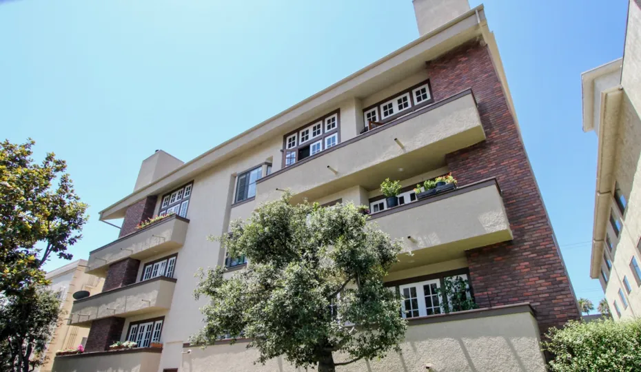 bick siding and large balconies adorn this building on a tree lined street