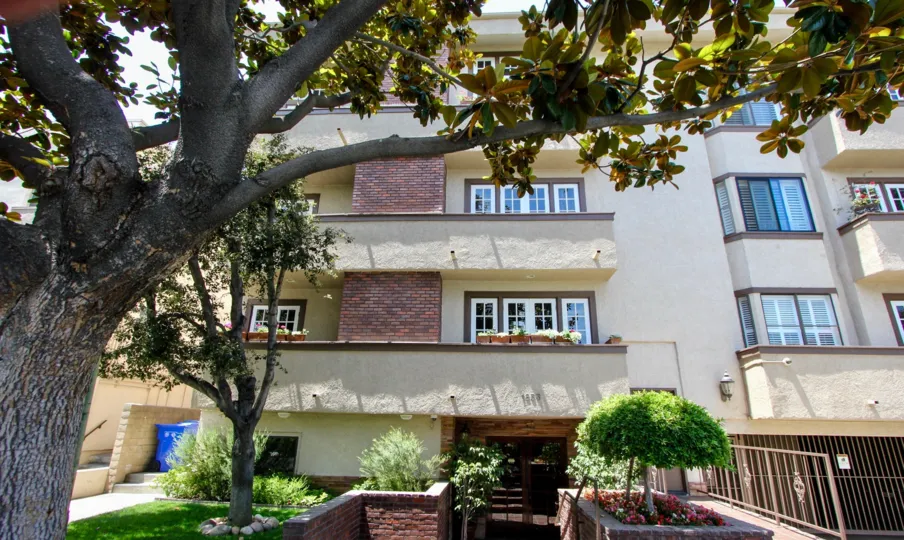 Apartment complex features large trees with landscaped gardens and under ground parking