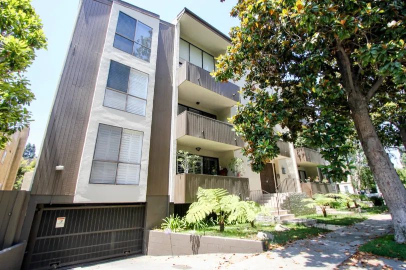 Tall buildling with gardens and sidewalk access to trees and lawn with underground parking