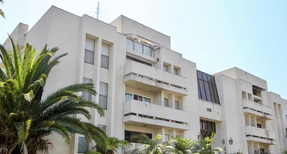 White building with windows and balcony with palm tree garden in West LA
