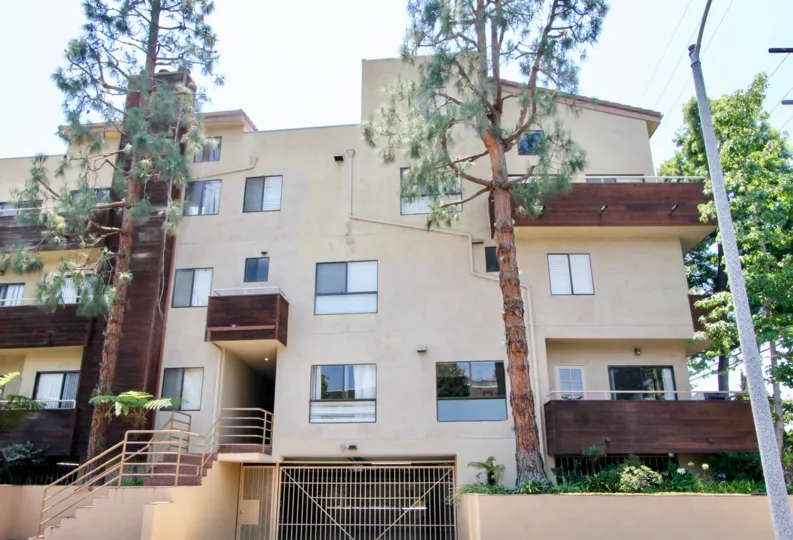 Tree lined wooden balconies apartment with several windows and gardens